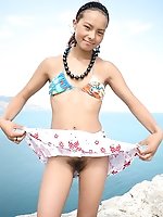 This sunburnt nude angel is standing in the mountains at the seaside and shows what a nice hairy pussy sheâ��s got under her skirt.