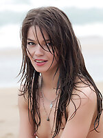 Nedda playfully poses with her gorgeous , athletic body on a sandy beach, with a charming smile and vibrant energy.