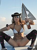 Adorable dark haired teen pirate in stockings playing with a tobacco pipe on the yacht.