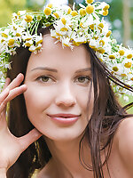 Adorable busty teen girl posing in only a wreath of daisies on her head in a sand quarry.
