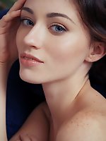 Zsanett tormay works her alluring magic as she undresses her white sweater, posing with finesse and refinement all over the blue sofa.