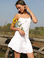 Attractive gal plays with her neat white dress while posing outdoors.