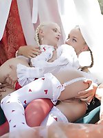 Two alluring damsels with the face of an angel, pretty braided hair, and delightfully petite bodies dressed in frilly, sheer lingerie and stockings.