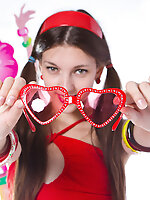 Adorable teen with red glasses in the shape of hearts and a tape recorder taking off her clothes.