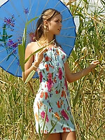 Girl in a light dress strolling outdoors, hiding from the sun under the sunshade and stripping