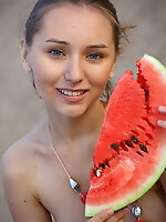 Charming teenage cutie enjoys getting naked and eating a watermelon outside in the dunes.